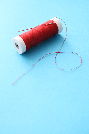 Isolated thread over textured blue background. Shallow depth of field, focus on image top