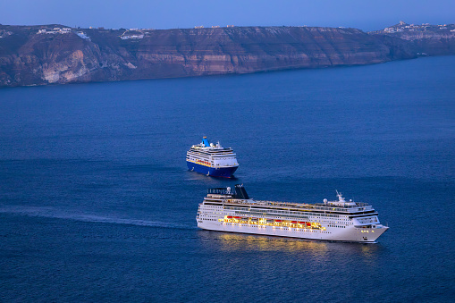 Santorini, Greece - September 5th 2023: Giant Cruise ships anchored on top of the Santorini Caldera in early morning sunlight