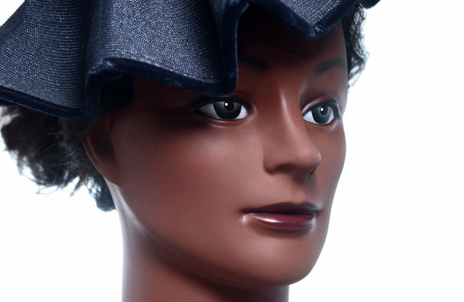 A head shot of a maniquin with a hat. Dark skin.