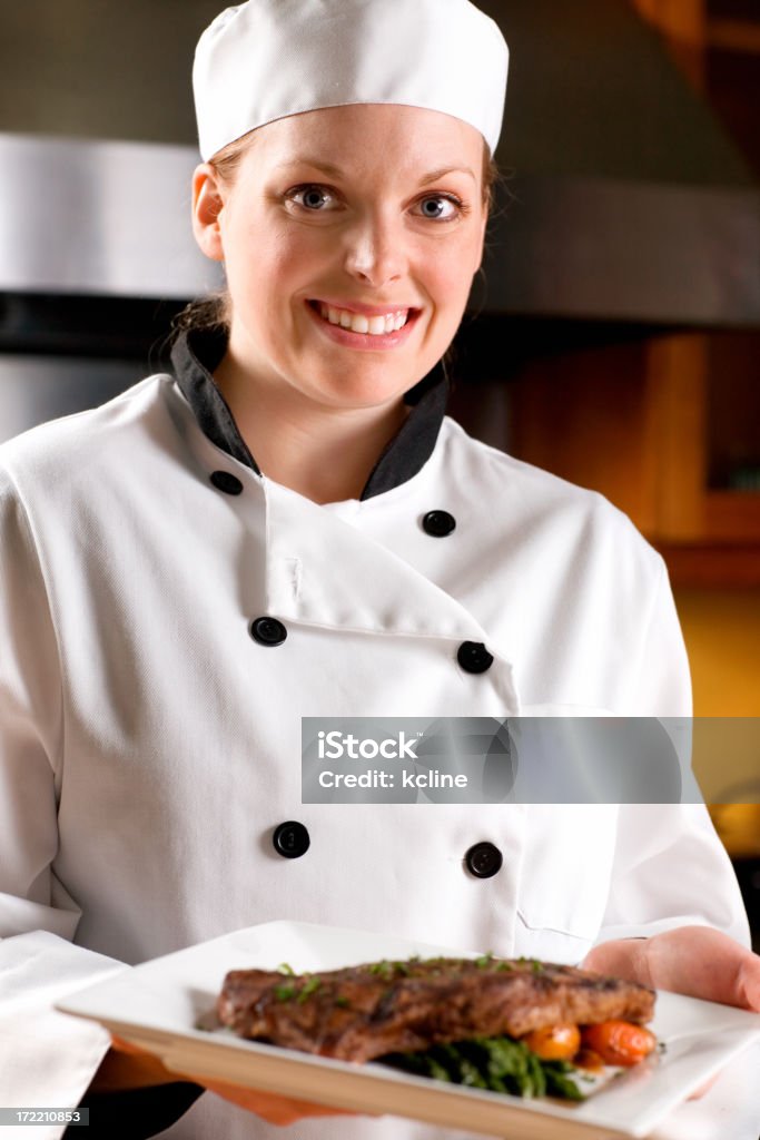 Smiling Chef A female chef smiling presenting a finished steak dinner.  Shallow dof with crisp focus on the entire chef. 20-24 Years Stock Photo