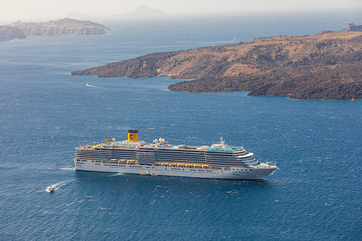 Santorini, Greece - September 3rd 2023: Giant Cruise ships anchored on top of the Santorini Caldera in early morning sunlight