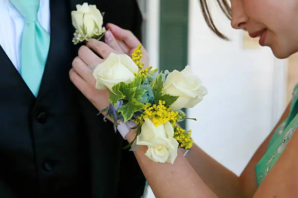 young woman pinning a boutonniere on her date