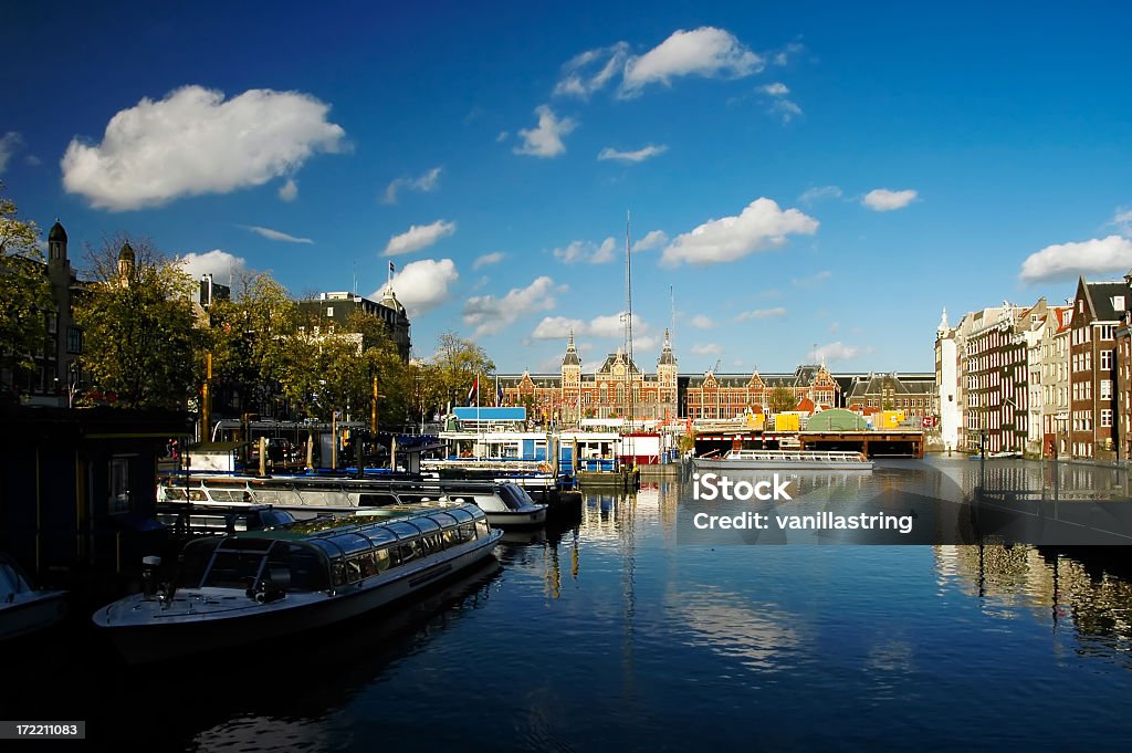 Amsterdam Canal One of the many canals in the beautiful city of Amsterdam.  The old train station is seen in the background. Amsterdam Stock Photo