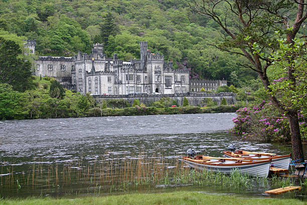 Kylemore Abbey on the lake, County Galway, Ireland "Kylemore Abbey in Connemara,County Galway, Ireland, with boats on the lake" kylemore abbey stock pictures, royalty-free photos & images