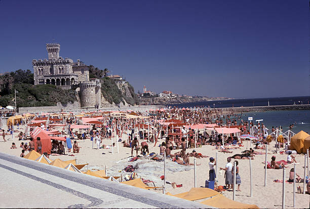 A large crowd gathers at the beach in Lisbon Portugal, on a hot summer day, to cool off in the chilly waters of the north Atlantic Ocean.