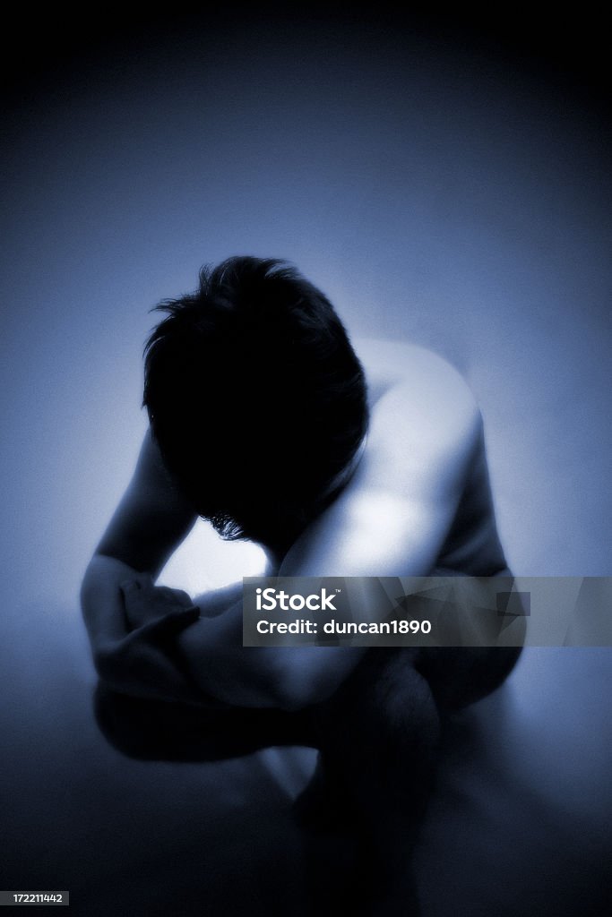 Loss Diffused portrait of a man crouching down and hidding his head. Has strong film grain effect at full size. Adult Stock Photo