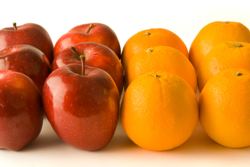 Apples and oranges side by side, lined up in a row. These foods are often used as concept comparison symbols for racism, discrimination, contrasts, prejudices, and conflicts, as well as individualism and idea variations. They are also citrus and tree fruits, groceries purchased as part of a healthy eating diet.