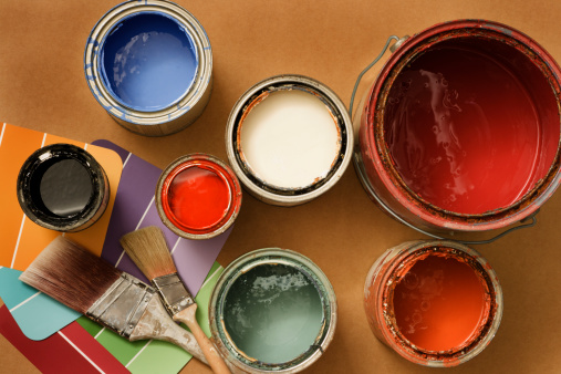 Open cans of paint, paint brushes and color swatches for home decorating or home improvement projects.