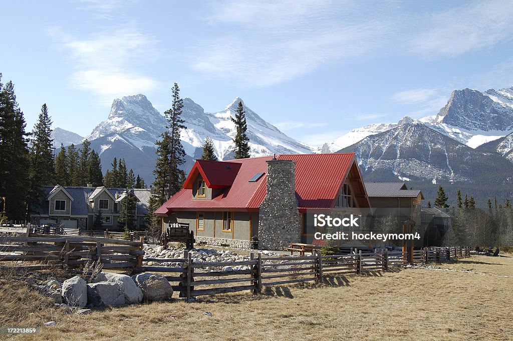 Ranch in the mountains Ranch home fenced property surrounded by snow covered mountains. Canmore Alberta near Banff National Park. Blue sky on a clear spring day. Canmore Stock Photo