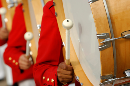 Marching band drummers bang away on bass drums.