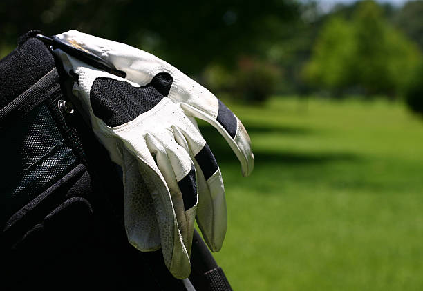 Golf Bag and Glove "Photo of a pair of golf gloves hanging on the side of a golf bag over looking the green fairway.  Glove is in focus, grass is out of focus." golf glove stock pictures, royalty-free photos & images
