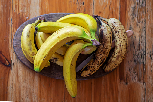 branch of bananas lies on a dish on a wooden table in the living room