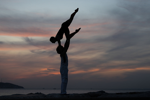 Young duo is practicing  acroyoga at beautiful sunset.