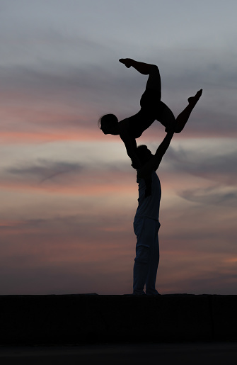 Young duo is practicing  acroyoga at beautiful sunset.
