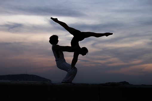 Young duo is practicing  acroyoga at beautiful sunset.