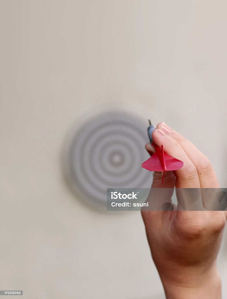 aiming for bullseye Hand holding dart. Blurry dartboard in the background Dart Stock Photo