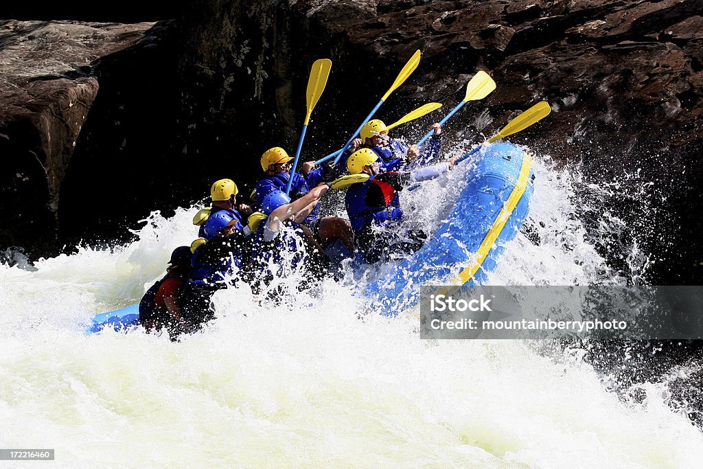 The Rock Rafters try to tap the rock with their paddles as they hold on to the boat. White Water Rafting Stock Photo