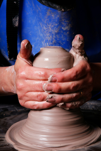 Close ups of hands making pottery on a wheel.
