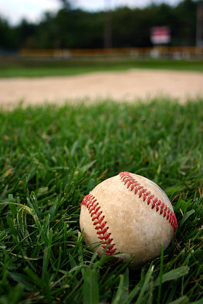 Baseball on field baseball on the infield near pitchers mound with fence and scoreboard in background baseball cage stock pictures, royalty-free photos & images