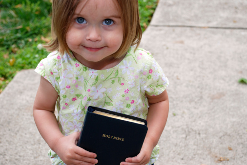 A little girl holds on to her father's Bible outside church.