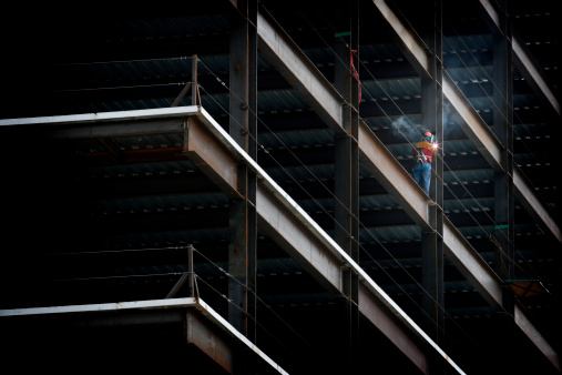 Iron worker welding an i beam on a high rise building