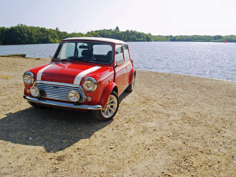 Old style Mini Cooper parked by a lake.