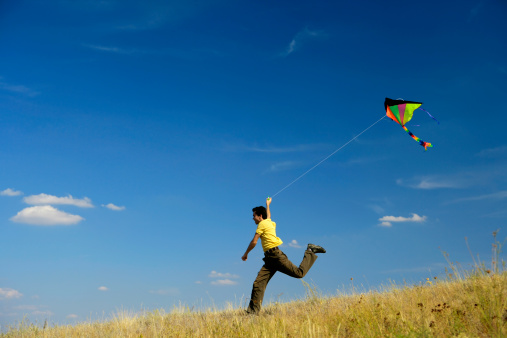 A young man flying kite at a sunny summer day.