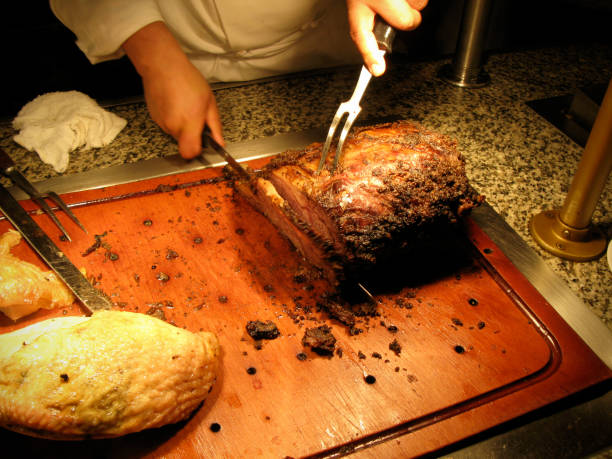 Food: Carving Prime Rib Chef carving a slab of prime rib. Turkey breast is just off to the left hand side. carving set stock pictures, royalty-free photos & images