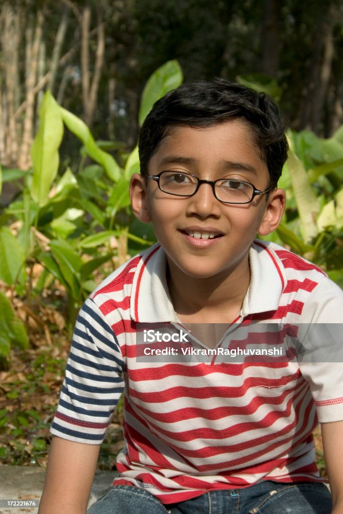Giovane allegro ragazzo indiano guardando la telecamera seduto nel parco - Foto stock royalty-free di Adolescente