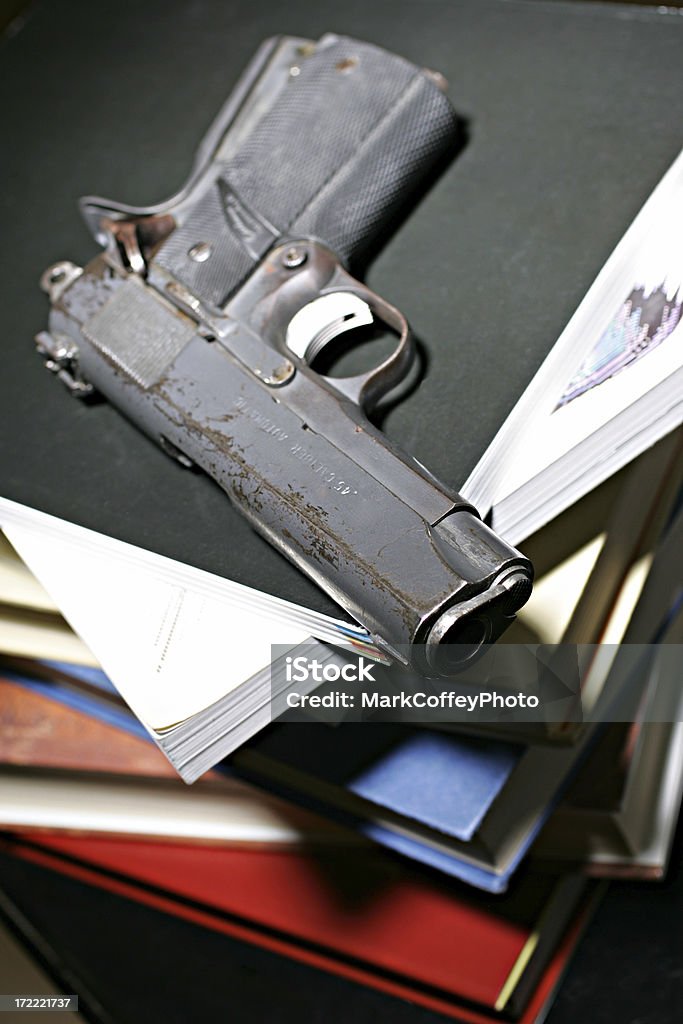 Handgun and books a 45 caliber handgun sitting on top of a stack of books Gun Stock Photo