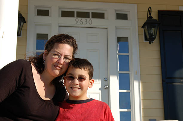 Single Mom and Son at their new house A newly single Mother stands with her son in front of the door of their new house.Other images with the same models: divorcee stock pictures, royalty-free photos & images