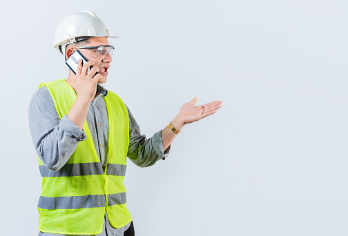 Young engineer calling on cell phone isolated. Civil engineer talking on phone isolated on white background