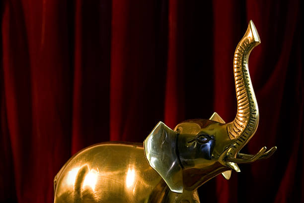 Gold elephant A shiny, gold colored elephant in front of a red velvet curtain. elephant figurine stock pictures, royalty-free photos & images