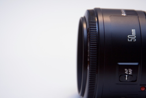 Closeup of 50mm lens.  Focus on top lens body and focus ring. Some texture visible on lens body.