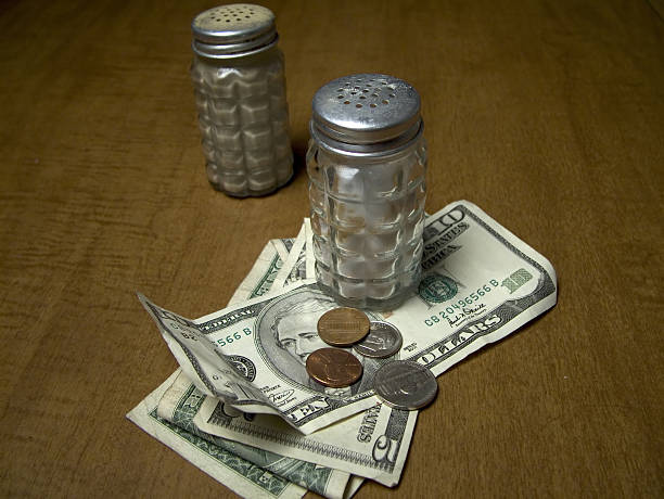 The Tip Salt and pepper shaker on a wood table. Salt shaker on money. leaving a tip stock pictures, royalty-free photos & images