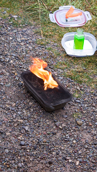 An on ground demonstration of how plastic spheres are activated for use in wild fire control.  
The round spheres contain potassium permanganate.  Before dropping from the helicopter, they move through a tube and injected with a green water and glycol solution, making the spheres combustable.  The exact combination of chemicals in each sphere determines how long it will take to ignite and how intensely the fire will burn.  From helicopters, they are dropped onto the ground to initiate a controlled burnout to remove debris from the ground - becoming a fire control line in that area.