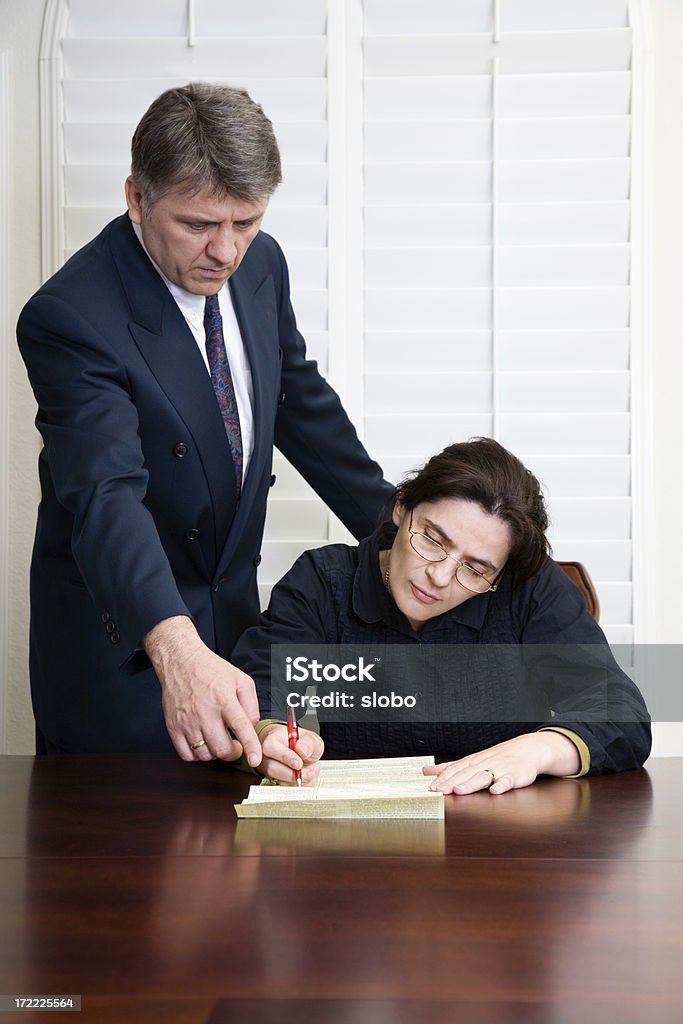 Mujer sentada en la mesa escrito con un hombre mirando sobre su. - Foto de stock de Acuerdo libre de derechos