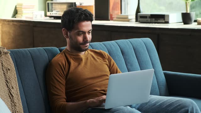 Man with Laptop Typing on Sofa