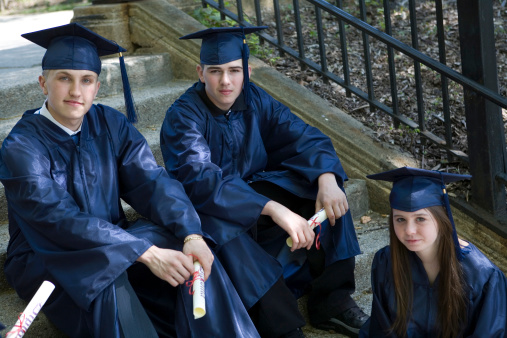Three graduates sitting on stairs