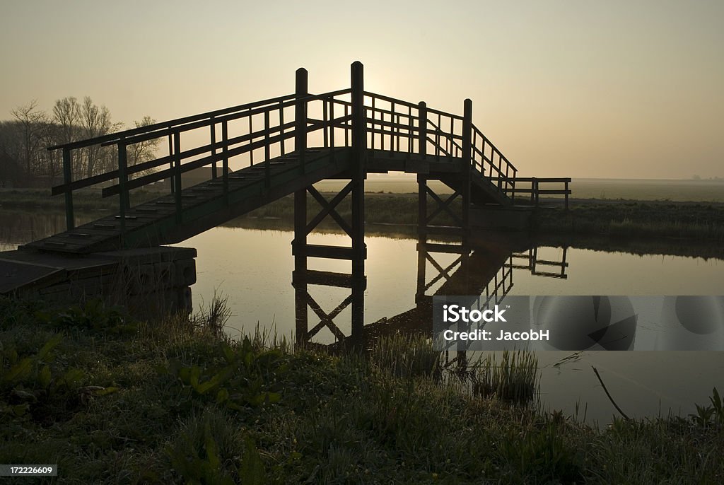 Wooden Bridge Silhouette of a wooden bridge over very quiet water during sunrise. Location is Burgerbrug, Netherlands Bridge - Built Structure Stock Photo