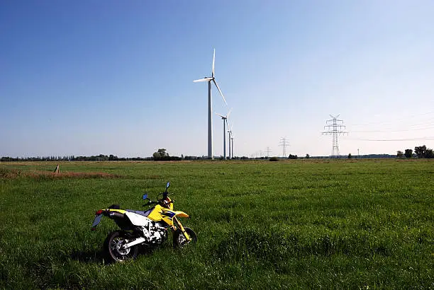 "through the field with a motocroos, windmills in the background."