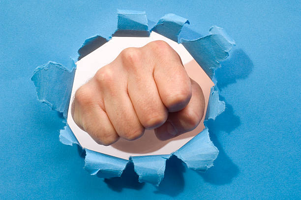 istock Fist punching through a ripped hole in a paper 172227392
