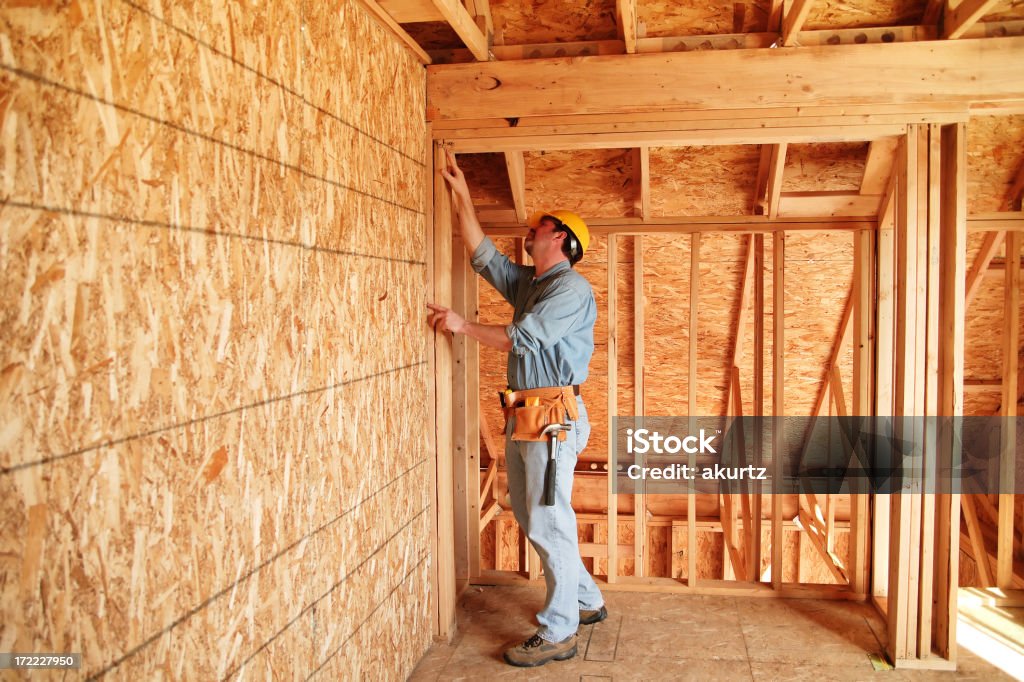 Keeping it level Construction worker building a new home wearing a yellow hard safty hat and a tool belt. Construction Material Stock Photo