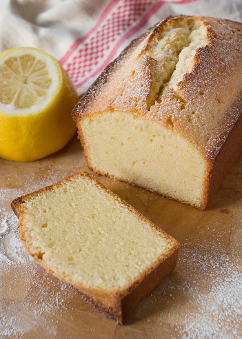 A freshley cut pound cake made with lemon on a wooden board.