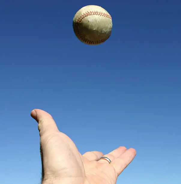 Photo of Close-up of hand trying to catch a ball in the sky