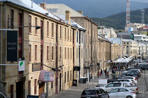 People walking at Salamanca Place, a precinct of Hobart, the capital city of Tasmania. Salamanca Place itself consists of rows of sandstone buildings, formerly warehouses for the port of Hobart Town that have since been converted into restaurants, galleries, craft shops and offices.