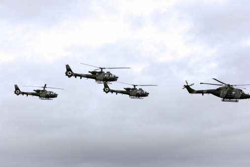 A flight of army helicopters in a stormy sky.