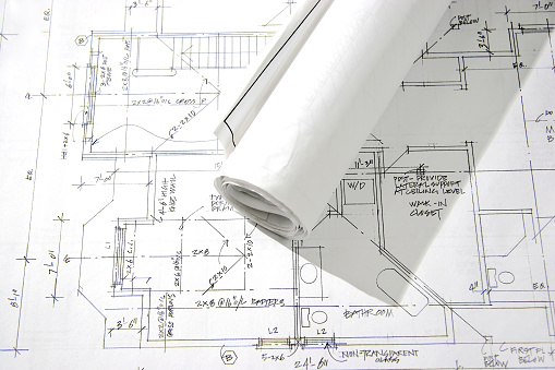 This is a photo of a rolled up blueprint laying on top of an architectural drawing.