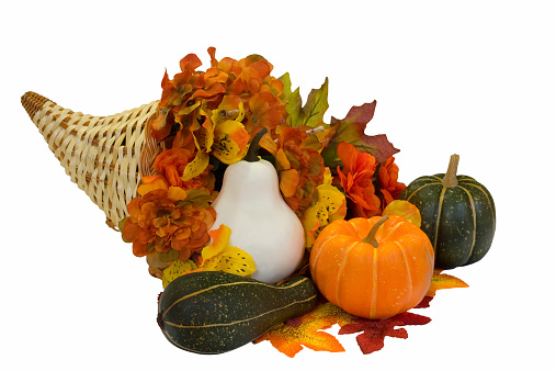 Autumn holiday Thanksgiving table place setting. Pumpkins, porcelain white plate, dry maple leaves, spice and apple on beige pastel background. Flat lay, top view, copy space.