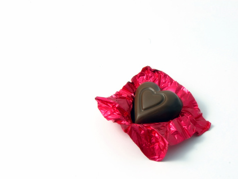 Heart shape chocolate on a red candy wrapping foil